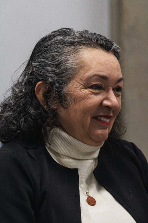 A imagem mostra uma mulher de cabelos cacheados grisalhos. ela está sorrindo